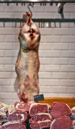 Fridge counter with variety of Irish angus beef meat and meat carcass in backgroundの写真素材