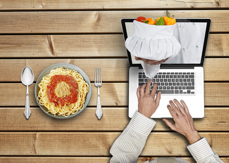 Businessman working on his laptop ordering pasta for lunchの写真素材