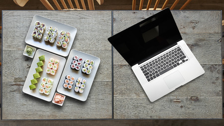 Delivery some plate of sushis and Laptop on two wooden tableの写真素材