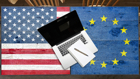 USA and Europe flagged wooden Table with laptop in restaurantの写真素材
