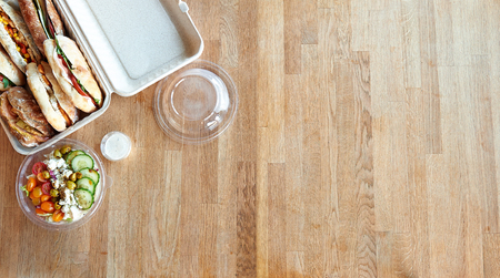 Order a sandwich box and a salad for lunch. View from above on wooden table