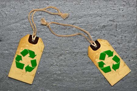 Two natural label tags and recycling symbol on Black textured granite slate