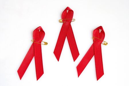 Red ribbons with golden pins for the Aids concept isolated on whiteの写真素材