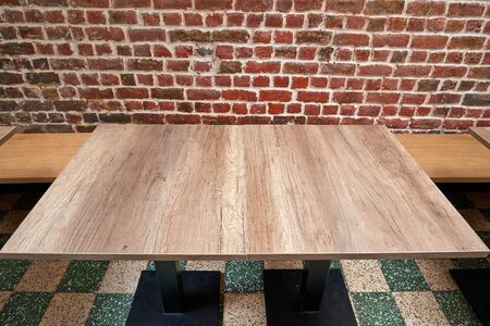 Nice rustic wooden table against red brick wall
