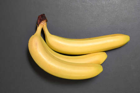 Bunch of ripe yellow bananas on black background. View from above