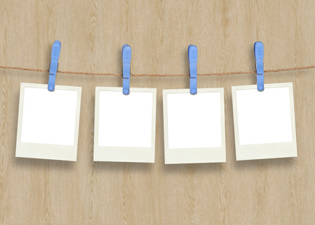 Four plastic clothespins and instant frame against wooden Backroundの写真素材