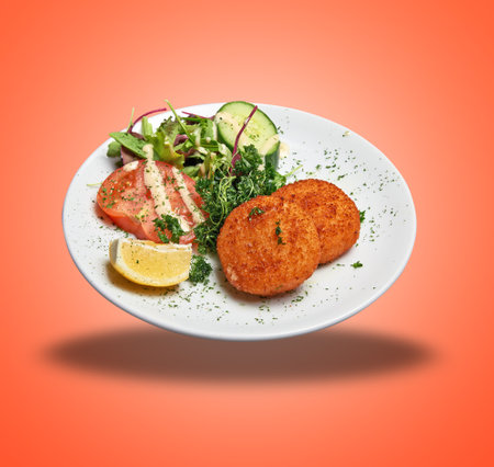 Floating White plate with two Cheese croquettes ans salad on orange gradient backgroundの写真素材