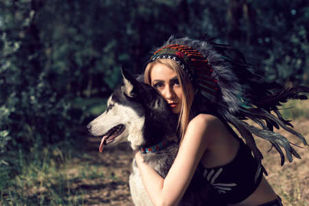 A girl with a dog in an Indian headdressの写真素材