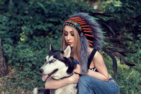 A girl with a dog in an Indian headdressの写真素材