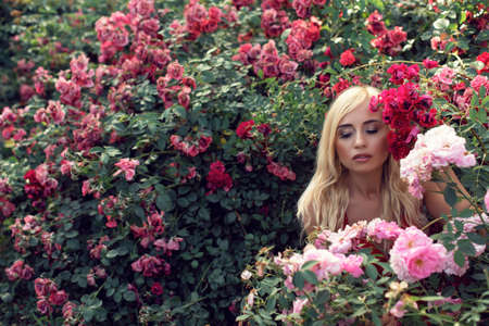 Mature blonde in the garden with rosesの写真素材
