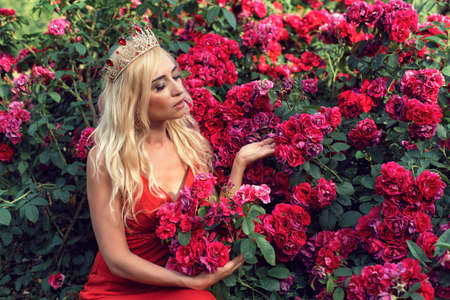 Mature blonde in the garden with rosesの写真素材