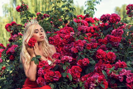 Mature blonde in the garden with rosesの写真素材
