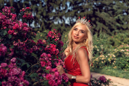 Mature blonde in the garden with rosesの写真素材