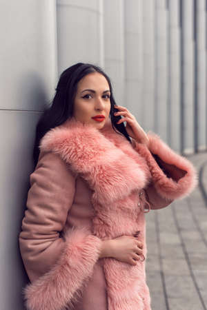 Brunette in the city in a pink coatの写真素材
