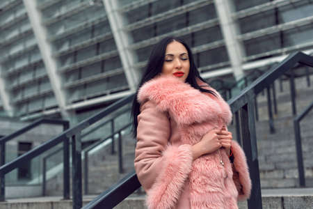Brunette in the city in a pink coatの写真素材
