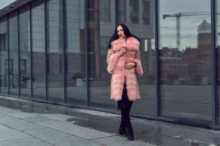 Brunette in the city in a pink coatの写真素材