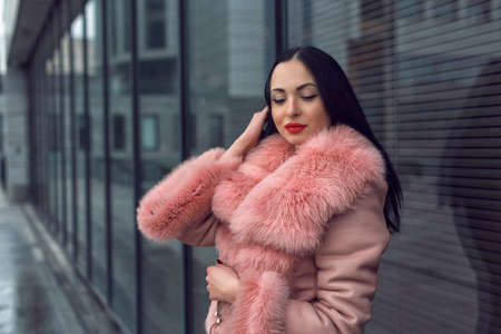 Brunette in the city in a pink coatの写真素材
