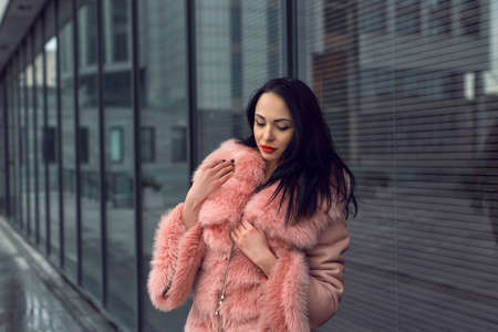 Brunette in the city in a pink coatの写真素材