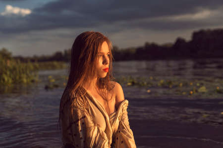 Girl in an embroidered dress on the lakeの写真素材