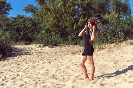 Girl on the sand wearing an Indian headdress