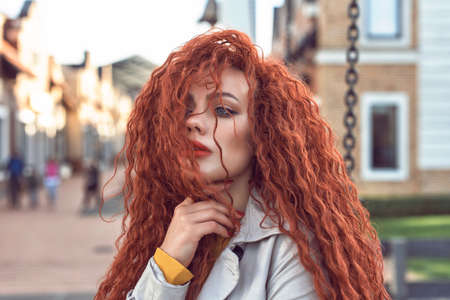 Redhead curly woman in the cityの写真素材