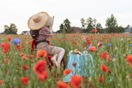 A young girl in a flowering poppy fieldの写真素材