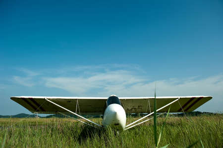 Light white aircraft landing on a green meadow, transportation, outdoorの写真素材