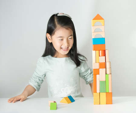 little Asian girl playing colorful wood blocks