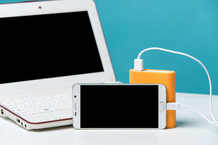charging smart phone with portable external battery on Modern laptop in the background.の写真素材