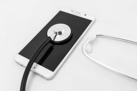 Medical stethoscope tool over the surface of a mobile smart phone, composition isolated over the...