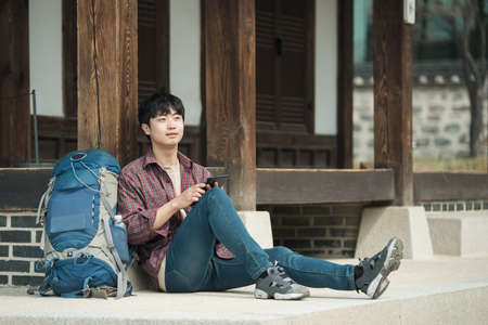 A young man backpacking in Korea. sitting in a Korean traditional house and using a tablet computer.の写真素材