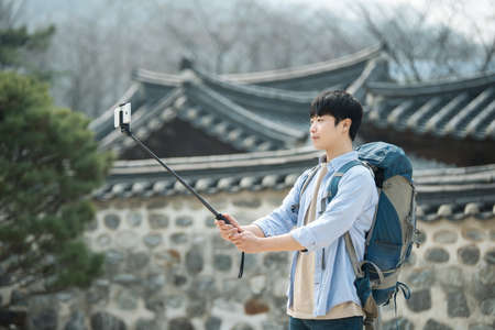 A young man who travels to Korea is taking pictures using his smartphone.の写真素材
