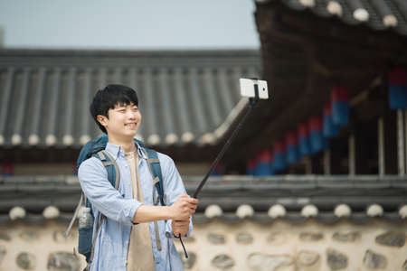 A young man who travels to Korea is taking pictures using his smartphone.の写真素材