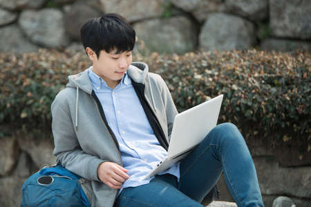 Asian man backpacking using laptopの写真素材