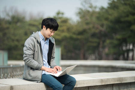 Asian man backpacking using laptopの写真素材