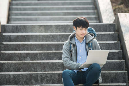 Asian man backpacking using laptopの写真素材