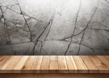 Wood table with cracked stone wall backgroundの写真素材