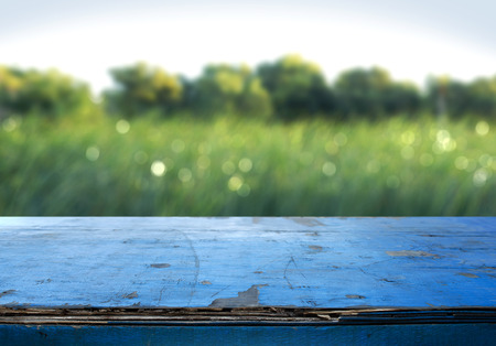 Blue painted wood table and green grass blurred backgroundの写真素材