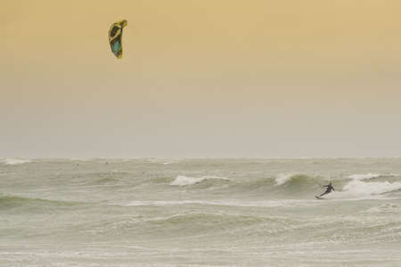Oleron, France - August 14, 2015: Kite surfer rides among the waves during a big storm with a yellow skyのeditorial素材