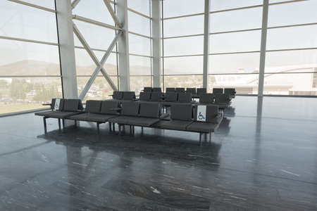 Row of grey chairs at airport with big windowsのeditorial素材