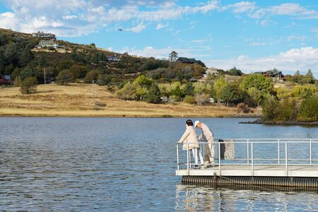 Old couple walking on a pier and dock at Lake Cuyamaca, reservoir and a recreation area in the eastern Cuyamaca Mountains, eastern San Diego County, California, USA. November 22nd, 2019のeditorial素材