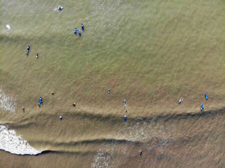 Aerial view of surfers waiting the waves in the dark, brown water in Bali, Indonesia. surfer on the...