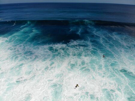 Aerial view of surfers on their board catching the waves,, big waves tropical blue ocean, Bali,...