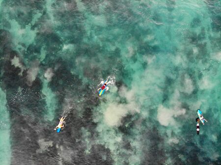 Aerial view of surfers waiting the waves in blue clear water. Surfer on the waves, surfers on their...