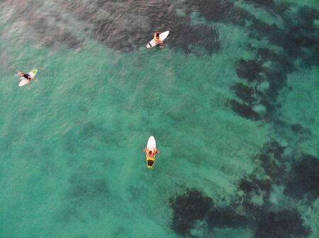 Aerial view of surfers waiting the waves in blue clear water. Surfer on the waves, surfers on their...