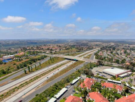 Aerial view of highway surrounded by villa in suburb. Intersection city transport road with vehicle...