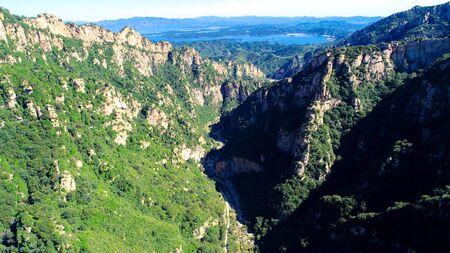 Aerial view of mountain with water reservoir on the background with beautiful blue sky. Landscape of mountain in natural reserve park. Miyun, Beijing, China.の写真素材