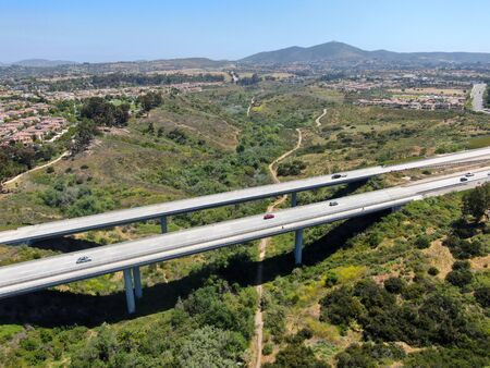 Aerial view of road highway bridge, viaduct supports in the valley among the green hills, transport...
