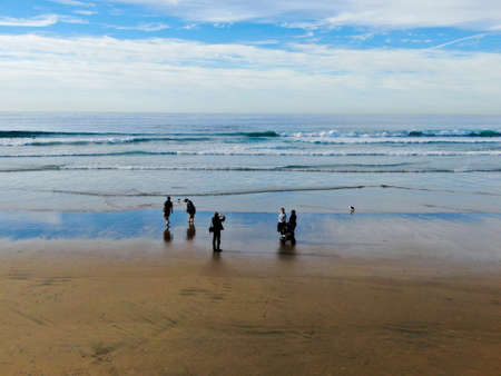 People enjoying and walking during peaceful moment on the beach. Beautiful sky on twilight time and reflection on the sea. La Jolla, San Diego, California, USA. January, 13, 2020の写真素材