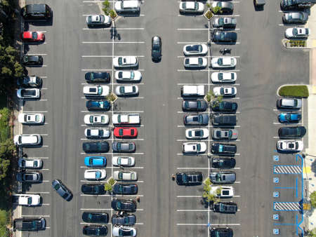 Aerial top view of parking lot at shopping mall with varieties of colored vehicles. People walking...
